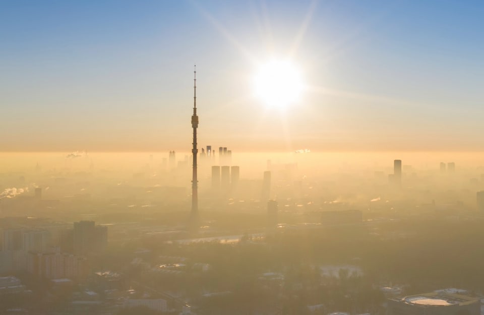 Vista dall'alto della torre di Ostankino, a Mosca, che spicca in un cielo terso sopra alla nebbia che avvolge il resto della città